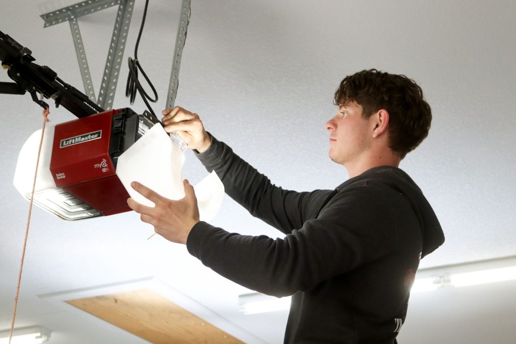 A garage door technician servicing a Liftmaster opener on a ceiling in Southwest Missouri