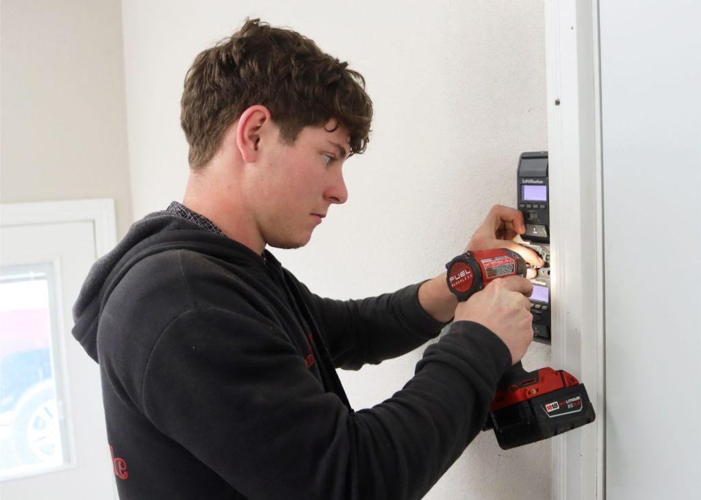 A garage door technician servicing an opener button in southwest Missouri
