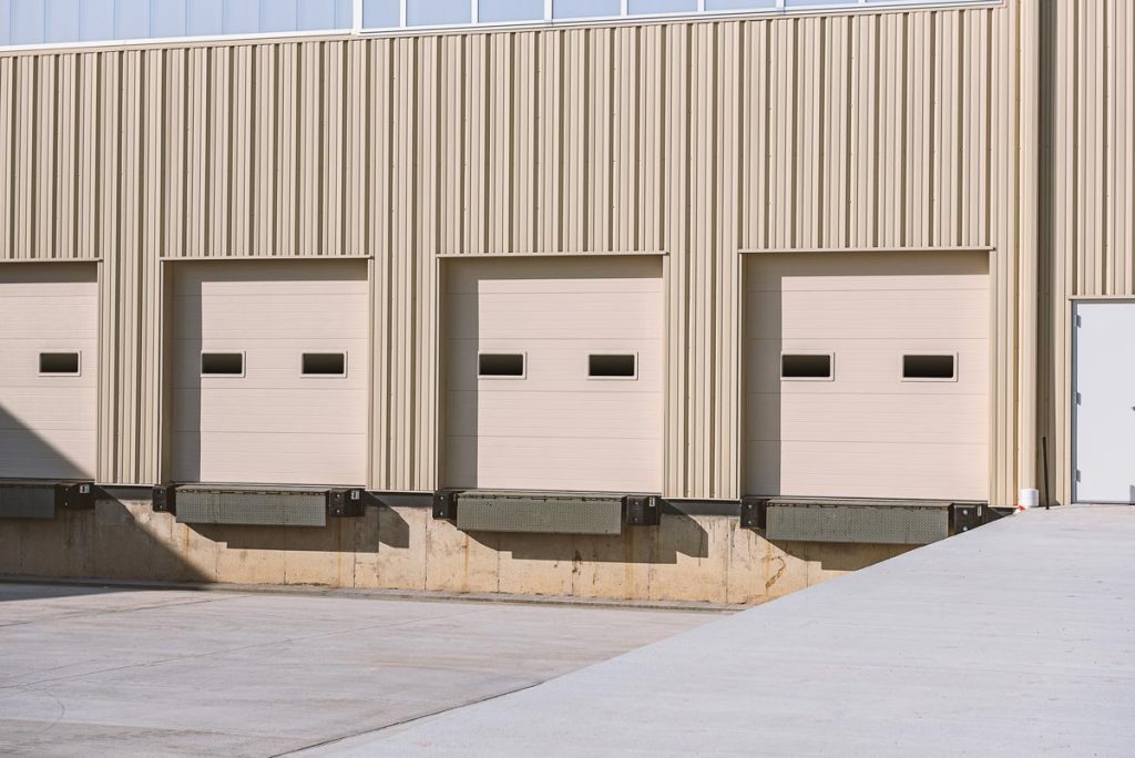 A loading dock with overhead doors featuring windows and micro grooved panels