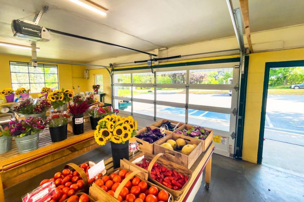 A small flower and produce shop with a commercial grade garage door featuring full view windows and powder coated frames