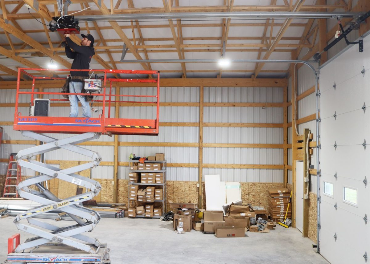 A technician in a scissor lift servicing an commercial overhead door opener near Springfield, Missouri