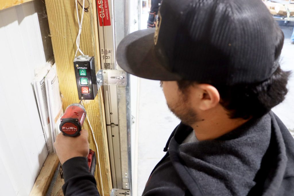 An overhead door technician servicing a commercial opener panel in Seymour, Missouri