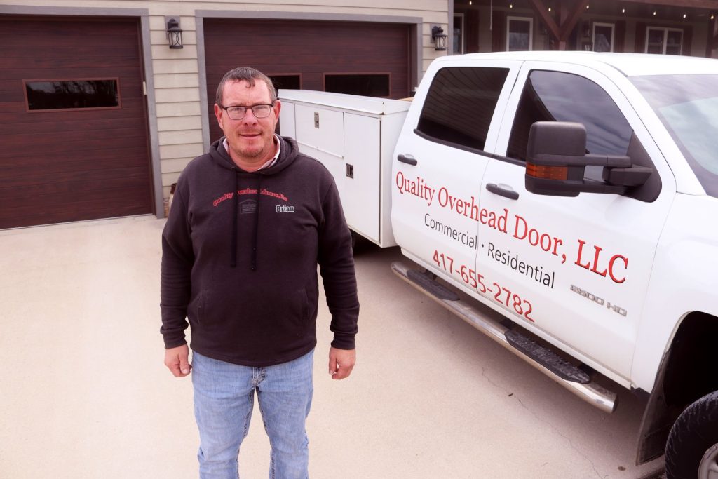 Brian Knepp, standing in front of of a residential garage door with his work truck in Seymour, Missouri