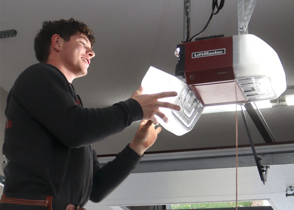 Happy technician servicing an residential garage door opener in Southwest Missouri