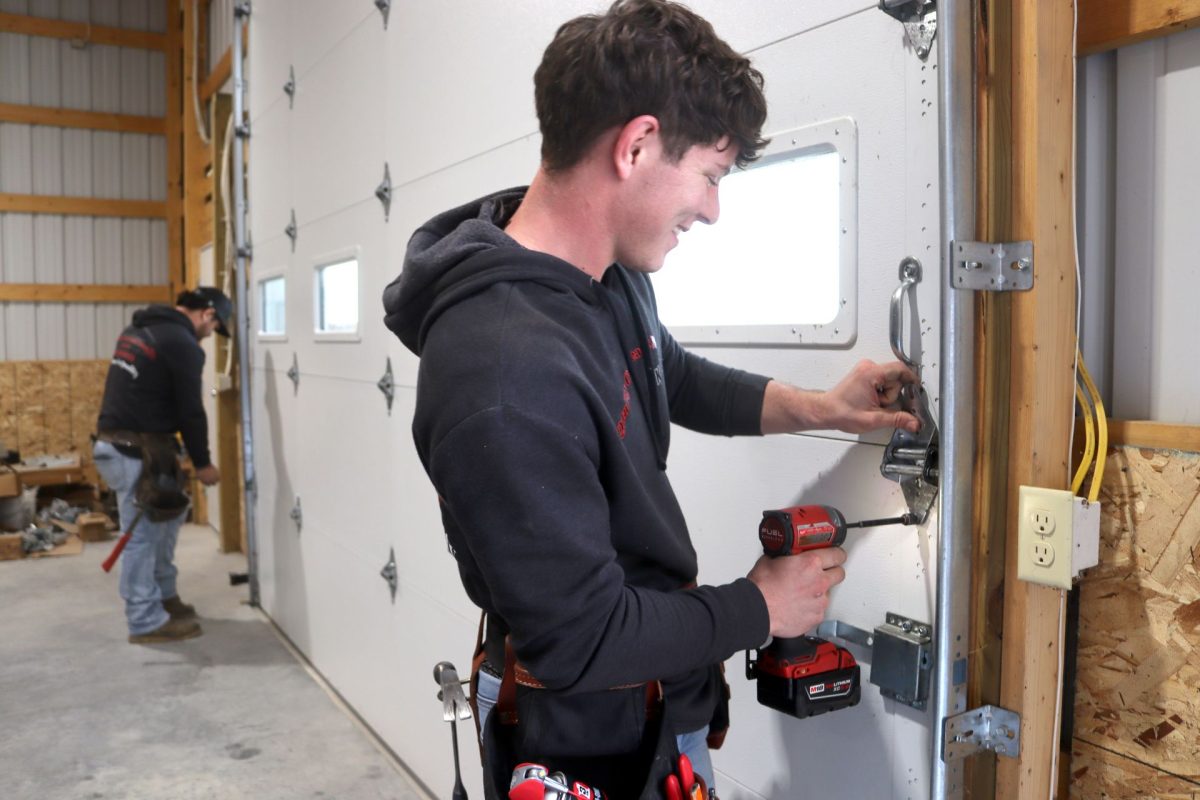 Two technicians installing overhead door hinges in southwest Missouri